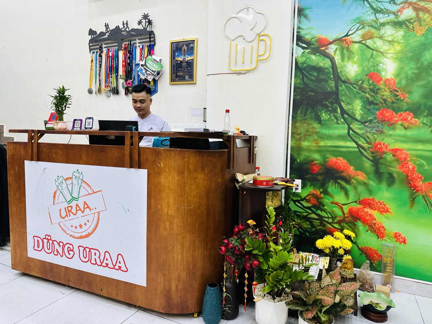 Quầy thu ngân DŨNG URAA với dàn huy chương chạy bộ marathon treo trên tường