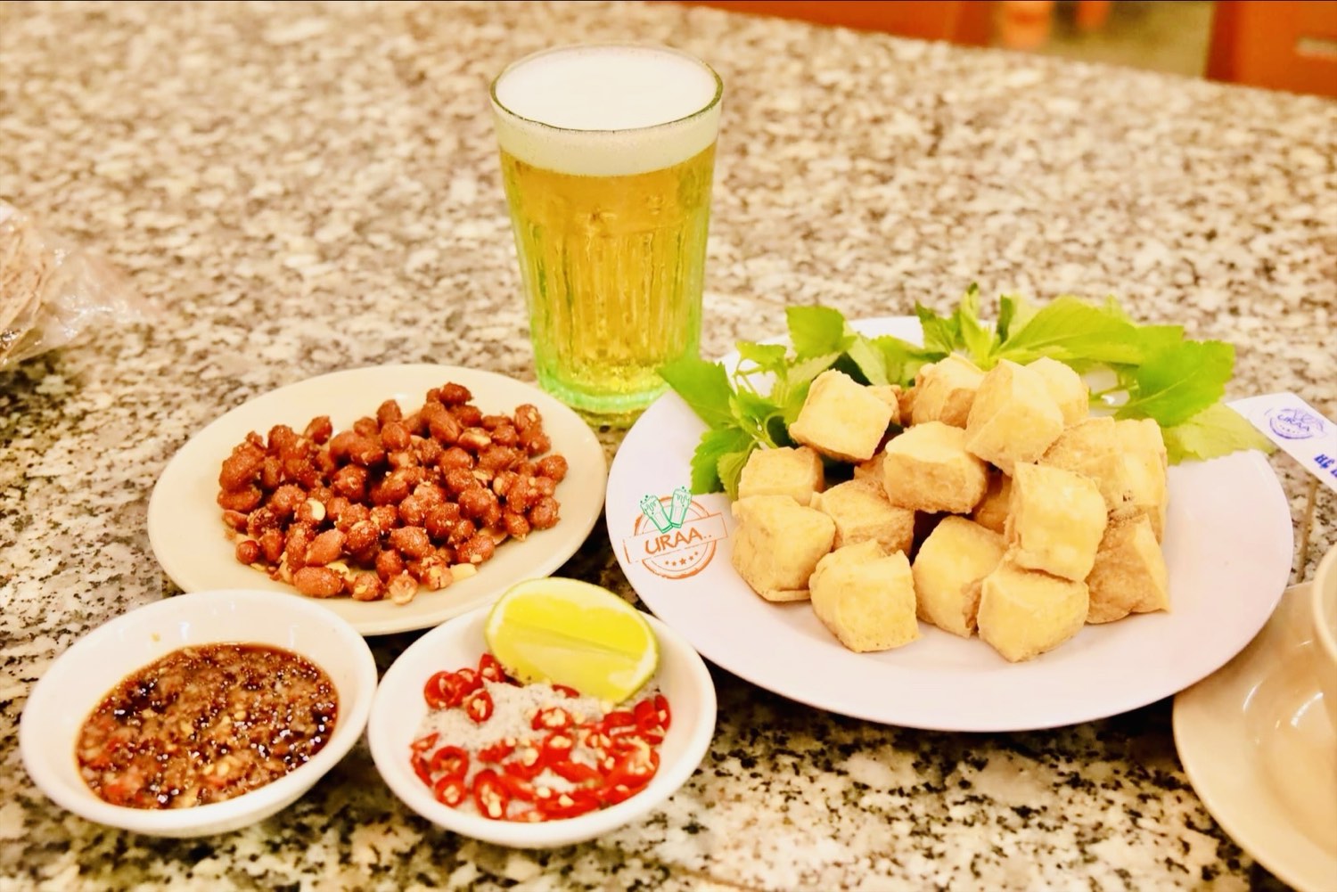 Mâm bia hơi Hà Nội tại DŨNG URAA Nha Trang — cốc bia hơi, đậu phụ rán vàng với tía tô, lạc rang và bát nước chấm