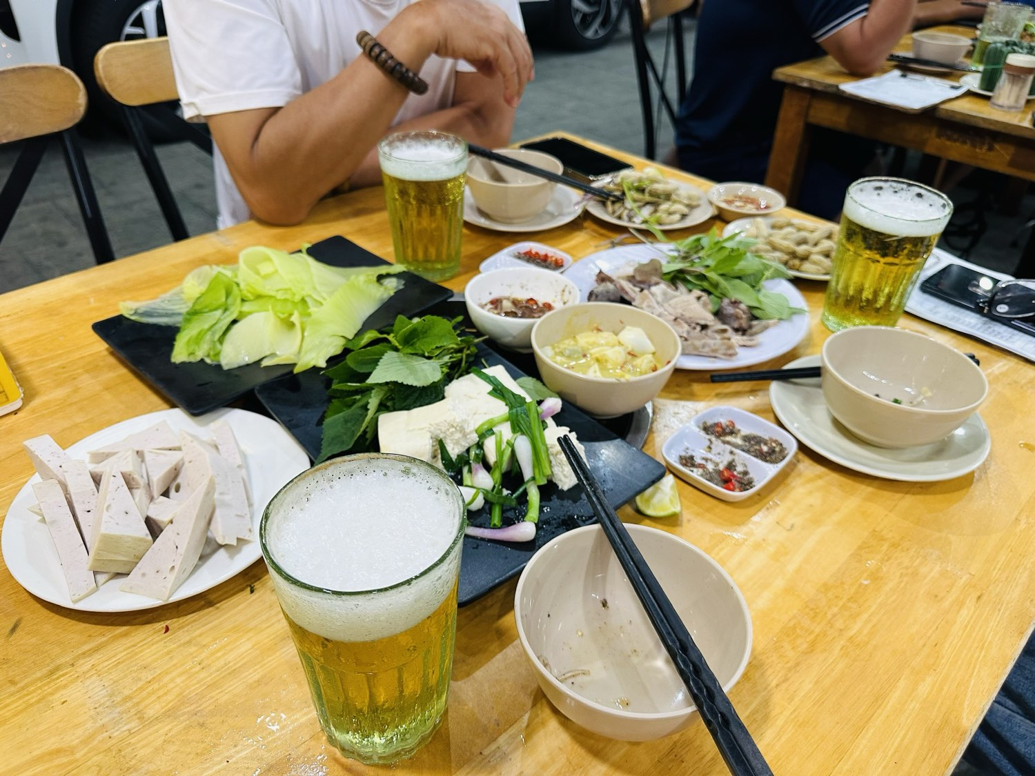 Bàn nhậu buổi tối tại DŨNG URAA — giò lụa, đậu phụ với tía tô, lòng luộc, lạc luộc và ba cốc bia hơi